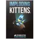 Imploding Kittens expansion pack box cover featuring a brown cartoon kitten in a space suit floating in outer space with planets and meteors in the background. The box has a dark gray background with large blue and white text displaying the game title "Imploding Kittens" at the top.