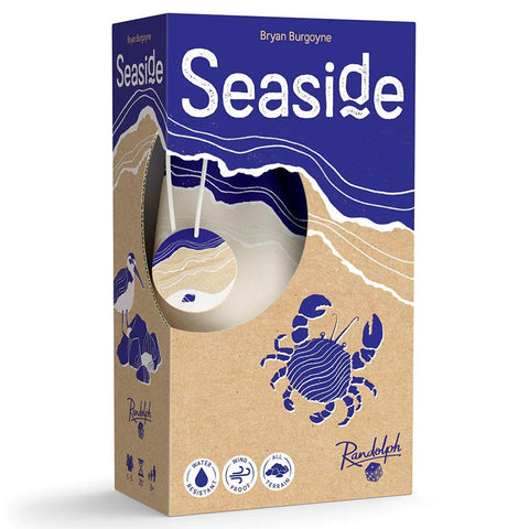 Seaside board game box by Bryan Burgoyne published by Randolph, featuring an artistic blue and tan design with layered wave patterns and a stylized crab illustration on sandy beach colors. The box has a distinctive oval window cutout on the front that reveals wooden game tokens inside. 