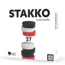 Stakko board game box showing stacked wooden discs in black, white, and red colors arranged in two different tower configurations.