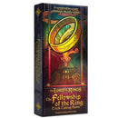 Box of "The Lord of the Rings: The Fellowship of the Ring Trick-Taking Game," featuring a stained-glass style illustration of the One Ring suspended above Mount Doom. The vibrant box art showcases rich colors of red, green, gold, and blue in a stylized design that evokes Middle-earth's aesthetic.