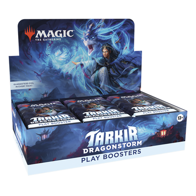 The box features dark blue artwork depicting a dragon and a spellcaster, with the Magic: The Gathering logo at the top. A display box of Tarkir: Dragonstorm Play Boosters with several sealed booster packs arranged inside.