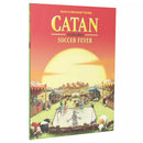 CATAN: Soccer Fever scenario expansion box cover featuring a medieval village setting with a soccer field in the center where cartoon-style characters are playing a match. The artwork shows a warm sunset sky with mountains in the background, colorful tents and buildings surrounding the field, and spectators watching from the sidelines. 