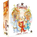 Box of Flamecraft board game showing the cover art and side panel. The main cover illustration features colorful cartoon dragons in white, red, and blue colors positioned in front of a fantasy marketplace with shops and townspeople.